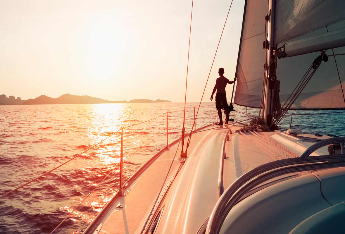 Big sailboat with a man standing in the front looking at the horizon
